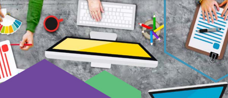 Busy design desk with multiple hands, color palette, computer monitors, keyboard, and documents.