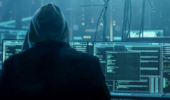 Hooded coder in front of monitors
