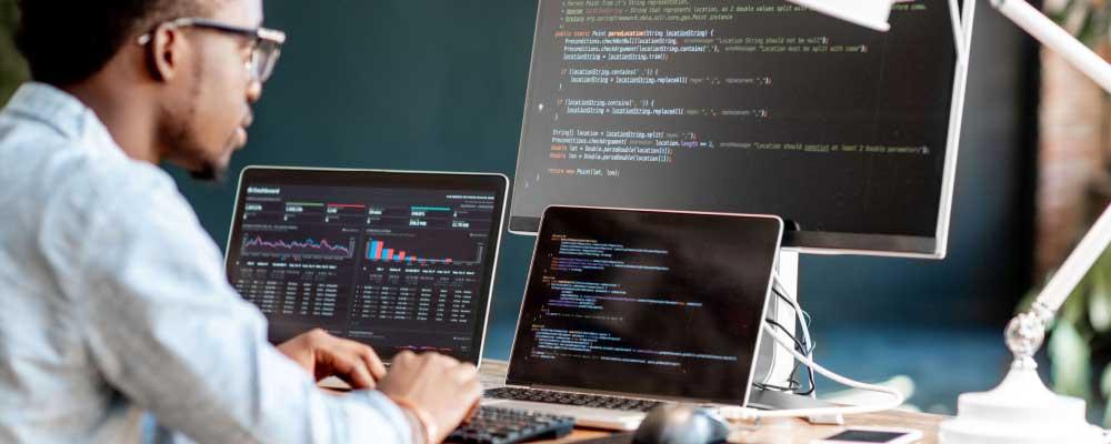 Developer working with multiple screens displaying code and data analysis.