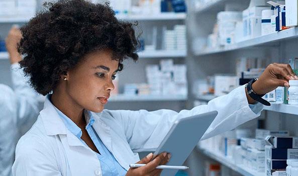 Pharmacist checking medication inventory with a tablet.