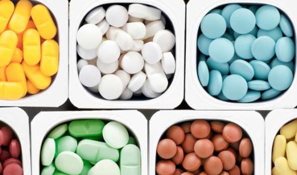 Colorful assortment of pills in individual white containers.