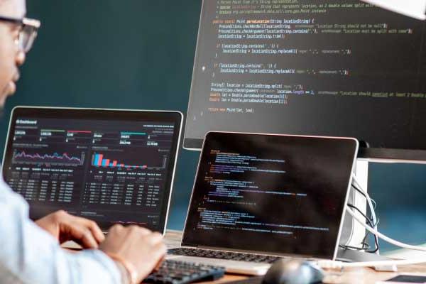 Developer working with multiple screens displaying code and data analysis.